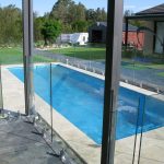 Frameless glass pool fence on travertine paving