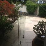 Frameless glass pool fence on paved poolside